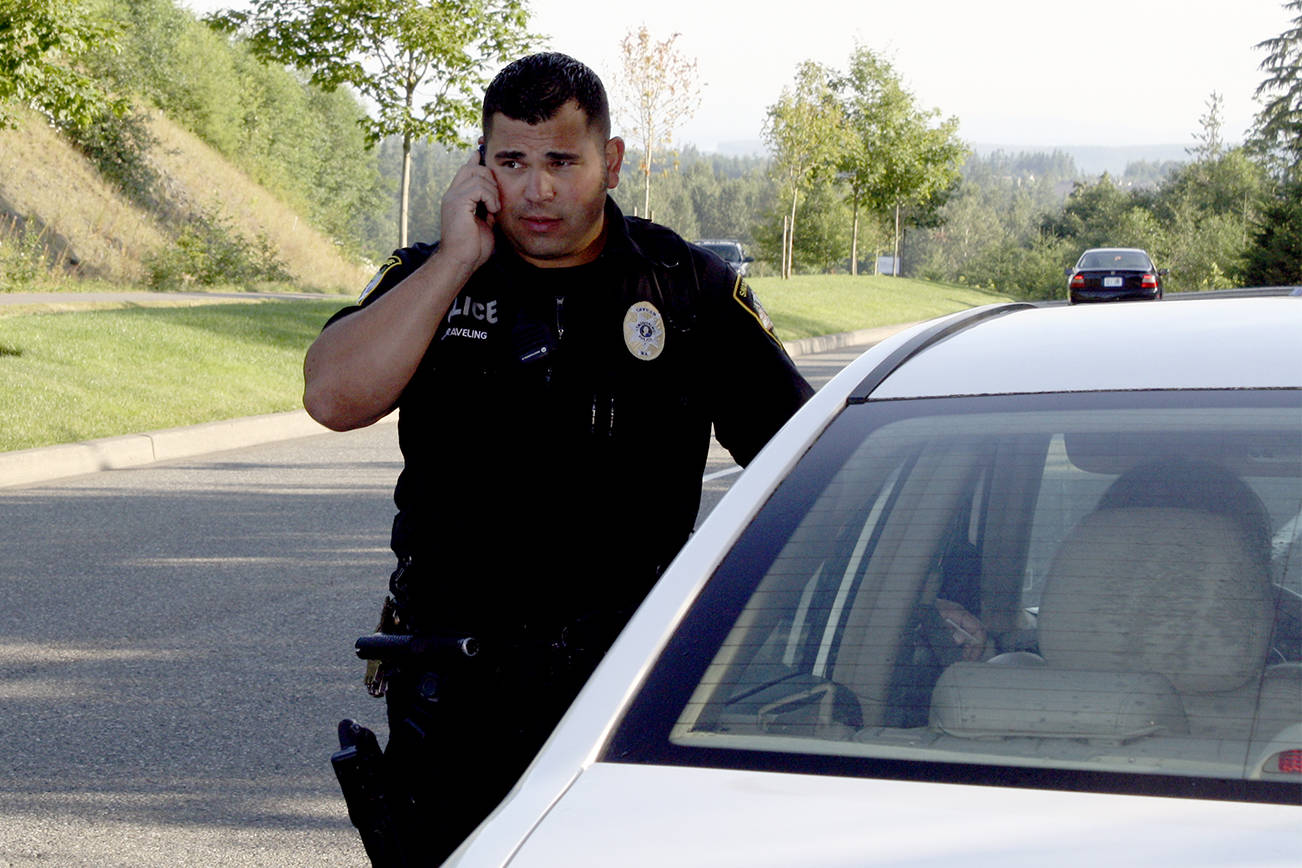 Snoqualmie Police Officer Nigel Draveling talks on a cell phone during a 2012 speed enforcement patrol. As of Sunday, talking on or using an electronic hand-held device is, in most cases, a violation of state law.                                (File Photo )