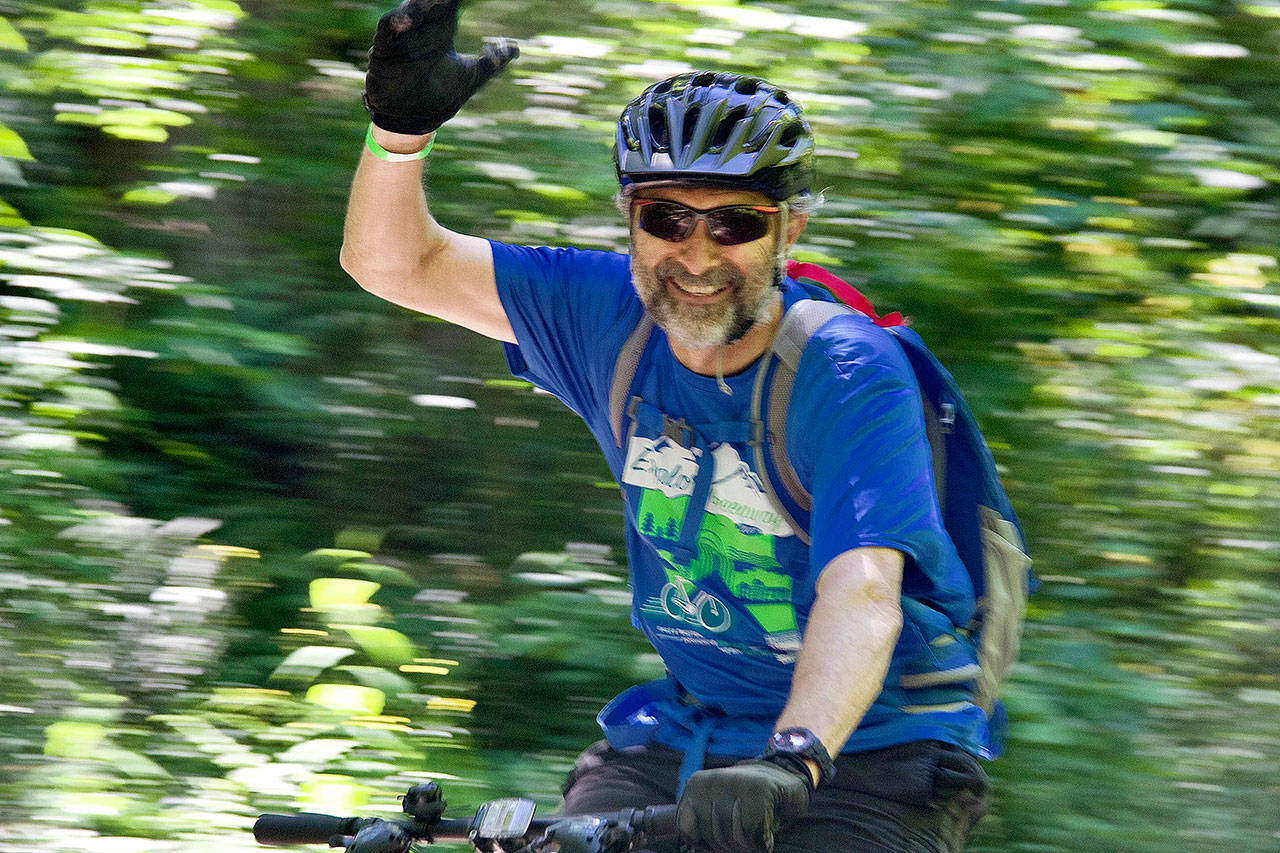 A cyclist grins and waves at the start of the Rails to Trails event spanning the Snoqualmie Valley June 24.                                Photo courtesy of Ray Lapine