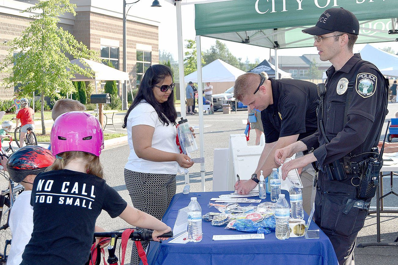 A family stops at sponsor Snoqualmie Police Department’s booth Tuesday.                                (Carol Ladwig/Staff Photo)