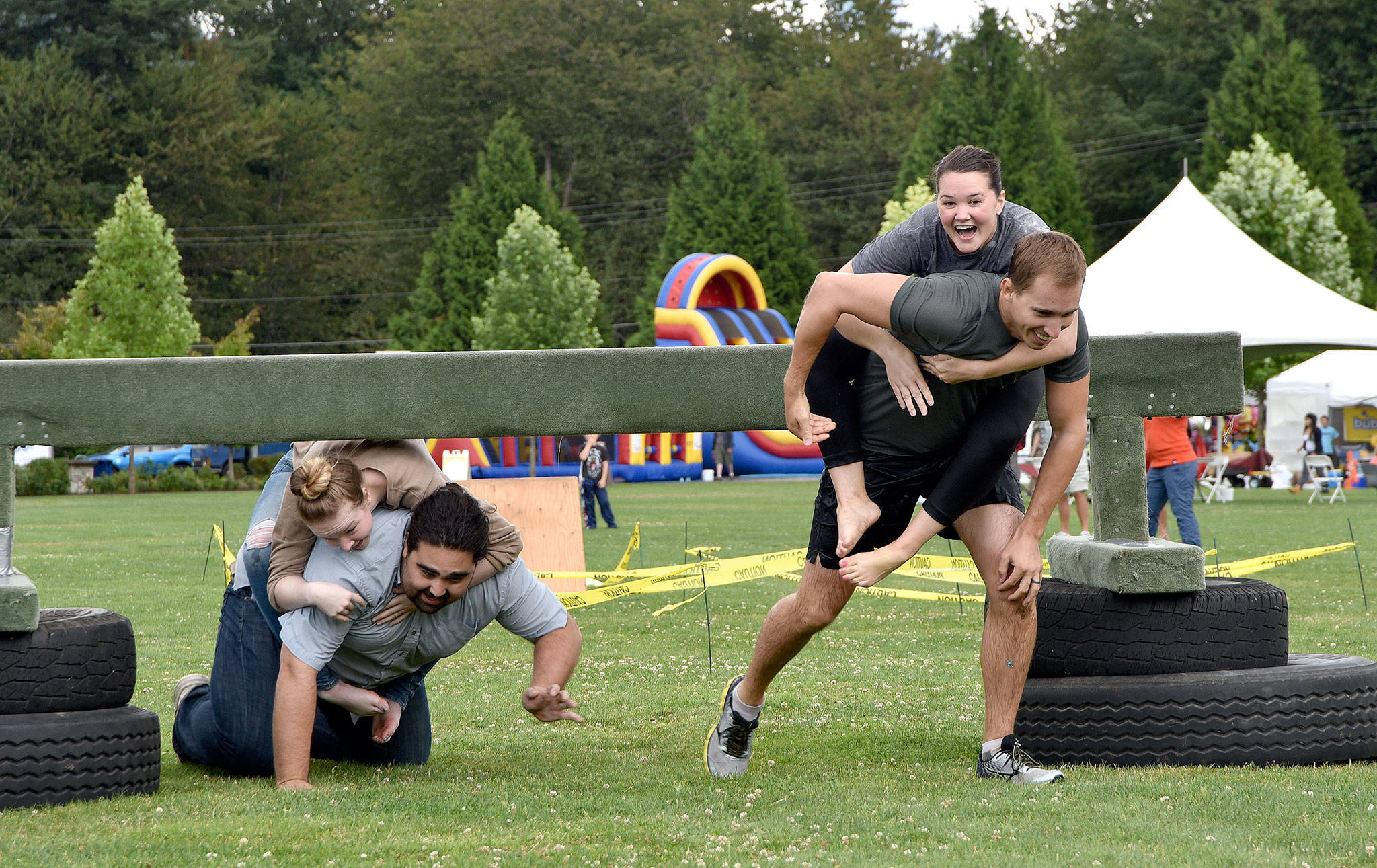 Chris and Jamie Teteak of North Bend smile hugely as they clear an obstacle, pursued by Alex Brewer and Lilly Knotts of Snoqualmie, in Sunday’s wife-carrying contest.                                (Carol Ladwig/Staff Photo)