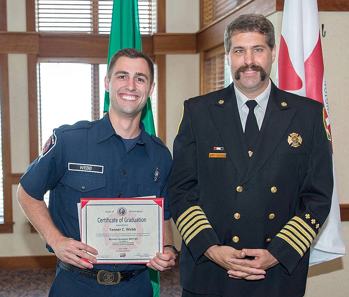 Snoqualmie Fire Chief Mark Correira, right, congratulates volunteer firefighter Tanner Webb on his graduation, with honors, from the state Fire Training Academy.                                (Courtesy Photo)