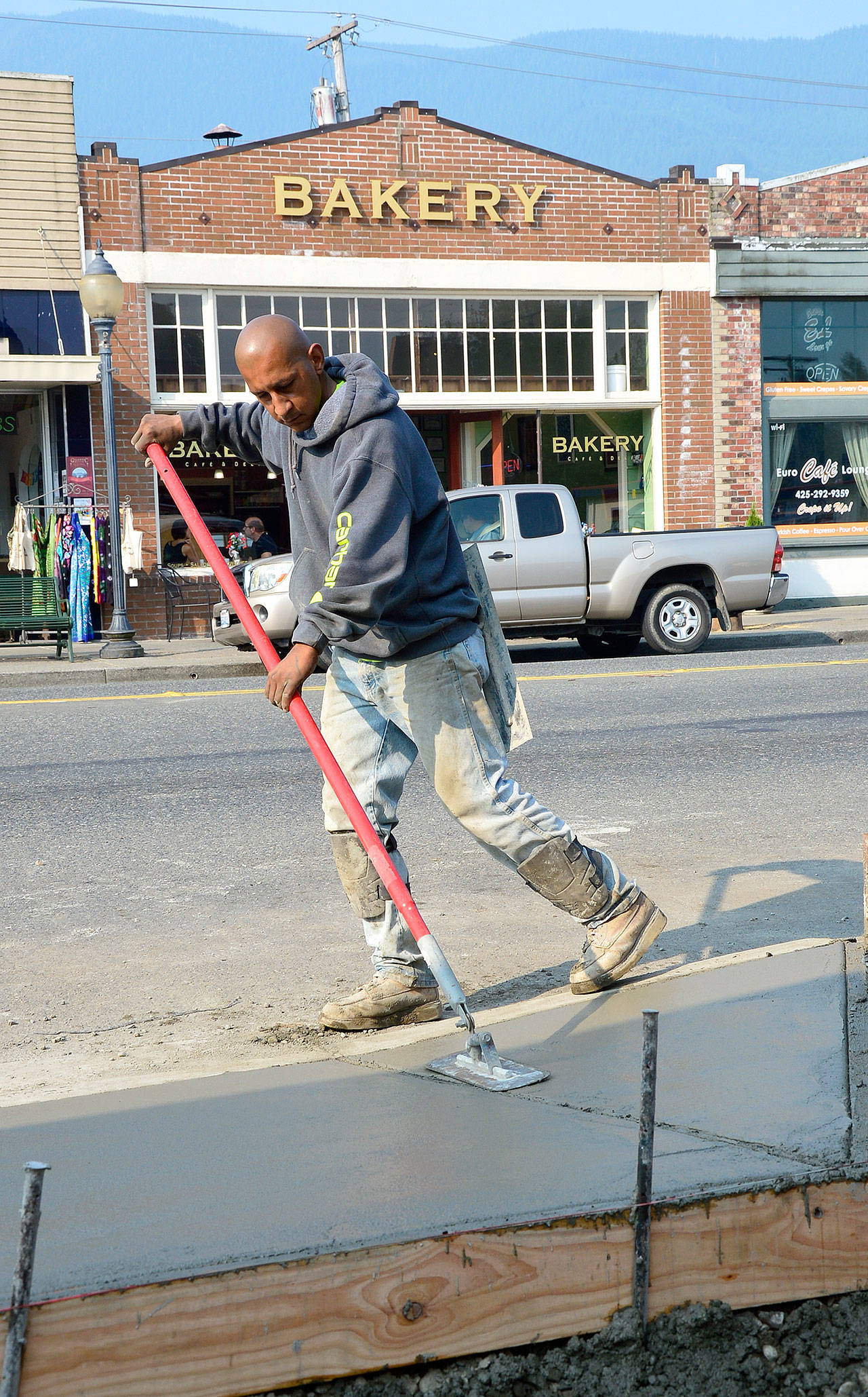A contractor smooths out the surface of a new sidewalk, part of North Bend’s downtown plaza project. Work on the project was stopped Friday, Aug. 18, because of an ongoing strike by Cal Portland cement workers that began a week ago.                                (Photo courtesy of Mary Miller)