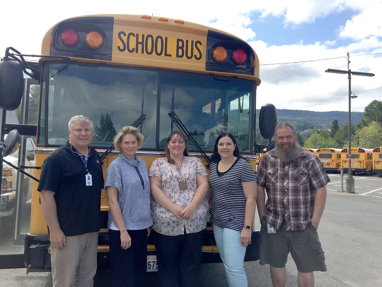 Snoqualmie Valley School District’s transportation staff stand out in the school bus lot as they prepare for the upcoming school year. From left: Jim Garhart, Maggie Clark, Robin Dawson, Angie Wing, and Douglas McKay. (Evan Pappas/Staff Photo)