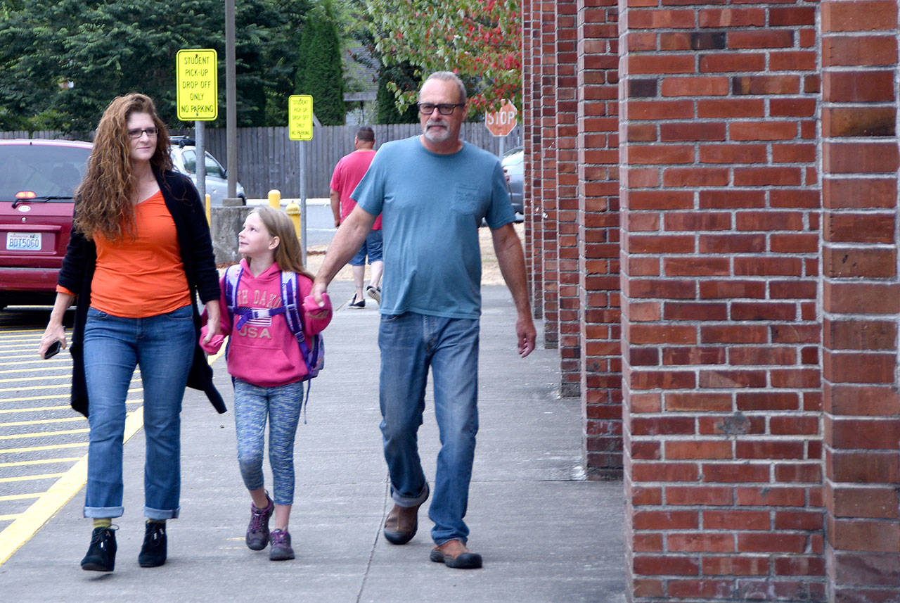 Kate Swanson, center, holds hands with her parents, Ann and Eric as she walks into Fall City Elementary School Wednesday. (Carol Ladwig/Staff Photo)