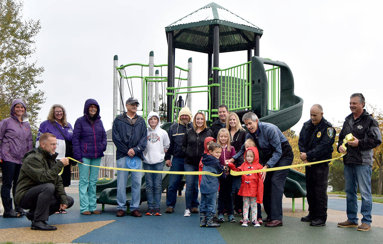 Parents, children and city staff gathered to cut the ribbon on the new playground equipment and surface installed at Ironwood Park, Wednesday, Oct. 25. The improvements were part of the city’s capital improvements plan. (Carol Ladwig/Staff Photo)