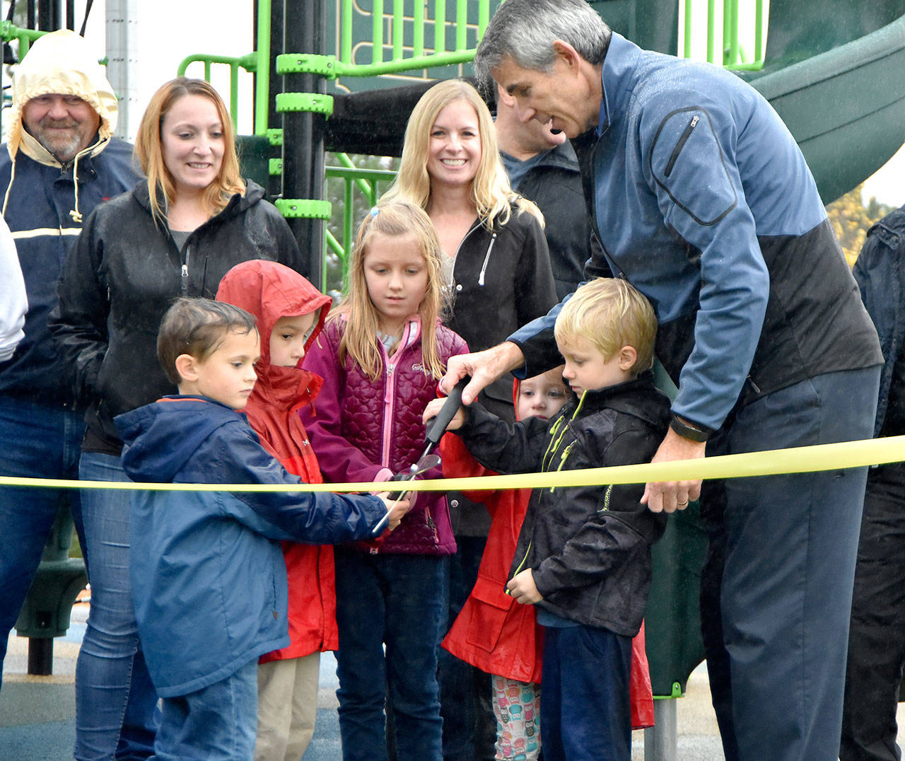 Each touching part of the giant ceremonial scissors, all of the children at Ironwood Park Wednesday had a hand in cutting the ribbon on park improvements. (Carol Ladwig/Staff Photo)