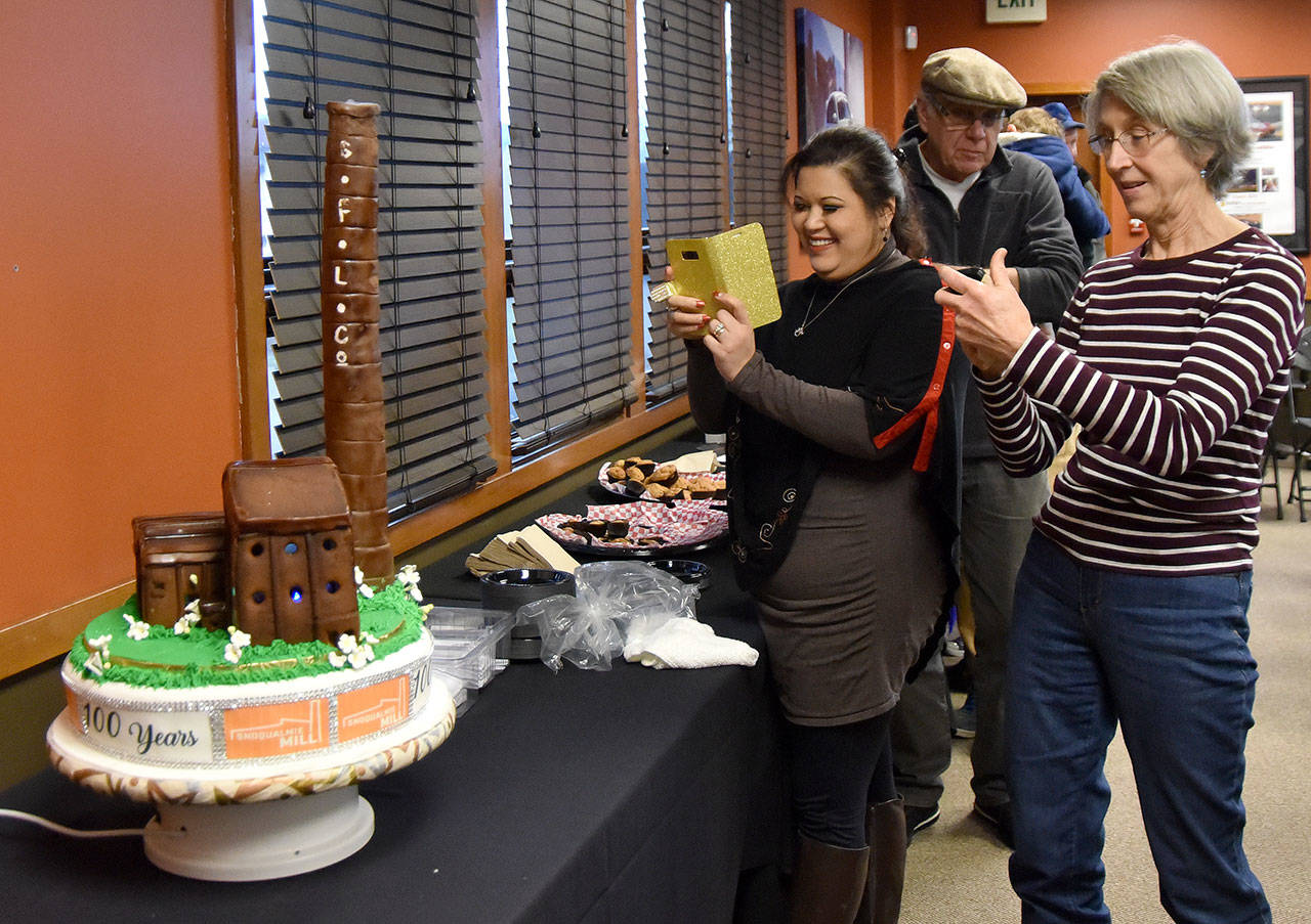 Cynthia Golpe, who baked the anniversary cake, photographs it before cutting and serving. (Carol Ladwig/Staff Photo)
