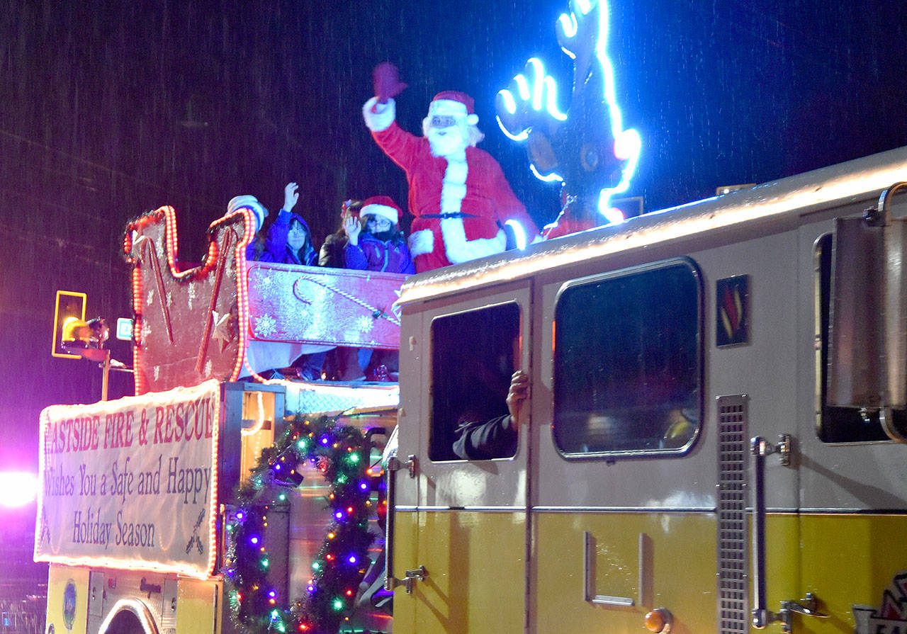 Santa and friends wave at Carnation residents from the Eastside Fire & Rescue Reindeer Engine, pulling into the Christmas in Carnation celebration Saturday evening. (Carol Ladwig/Staff Photo