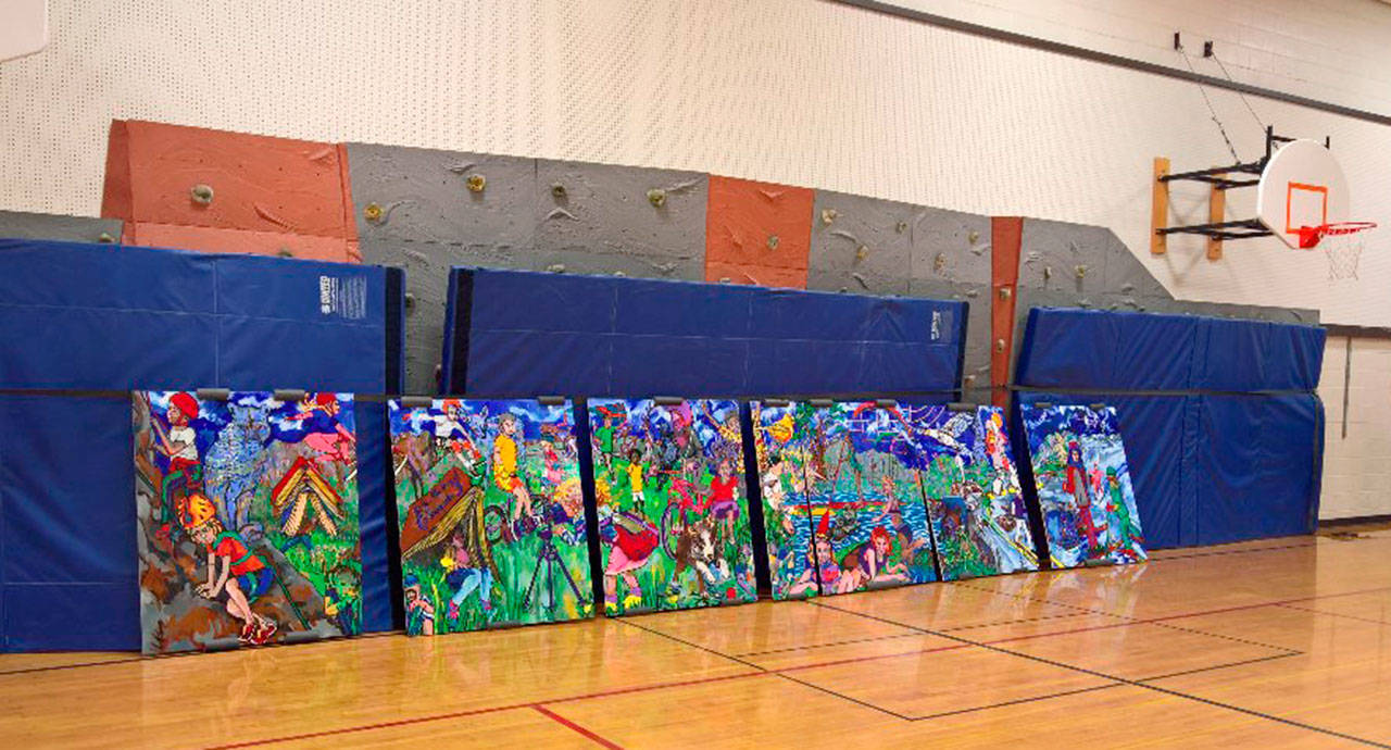 The seven individual wood panels that form the mural sit on the floor before being put up on the wall inside the gym. (Courtesy Photo)