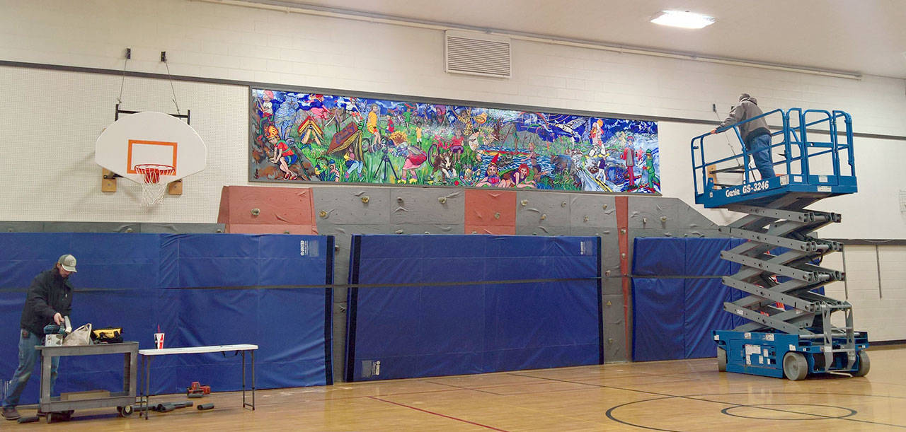 School district maintenance workers install the mural above the Opstad gym’s rock wall on Dec. 28. (Courtesy Photo)