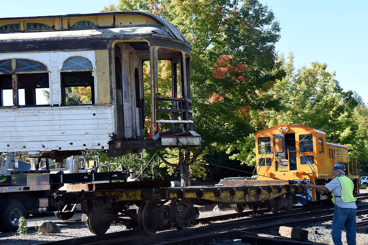 Volunteers help control the car as the crane lifts it onto the flatbed car on the tracks. (Carol Ladwig/Staff Photo)