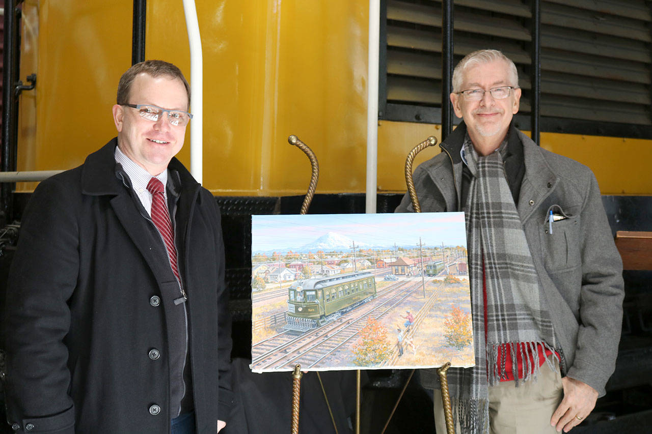 Northwest Railway Museum Executive Director Richard Anderson and artist J. Craig Thorpe unveil the finished artwork of the Interurban car 523 commissioned to promote the restoration of the car. (Evan Pappas/Staff Photo)