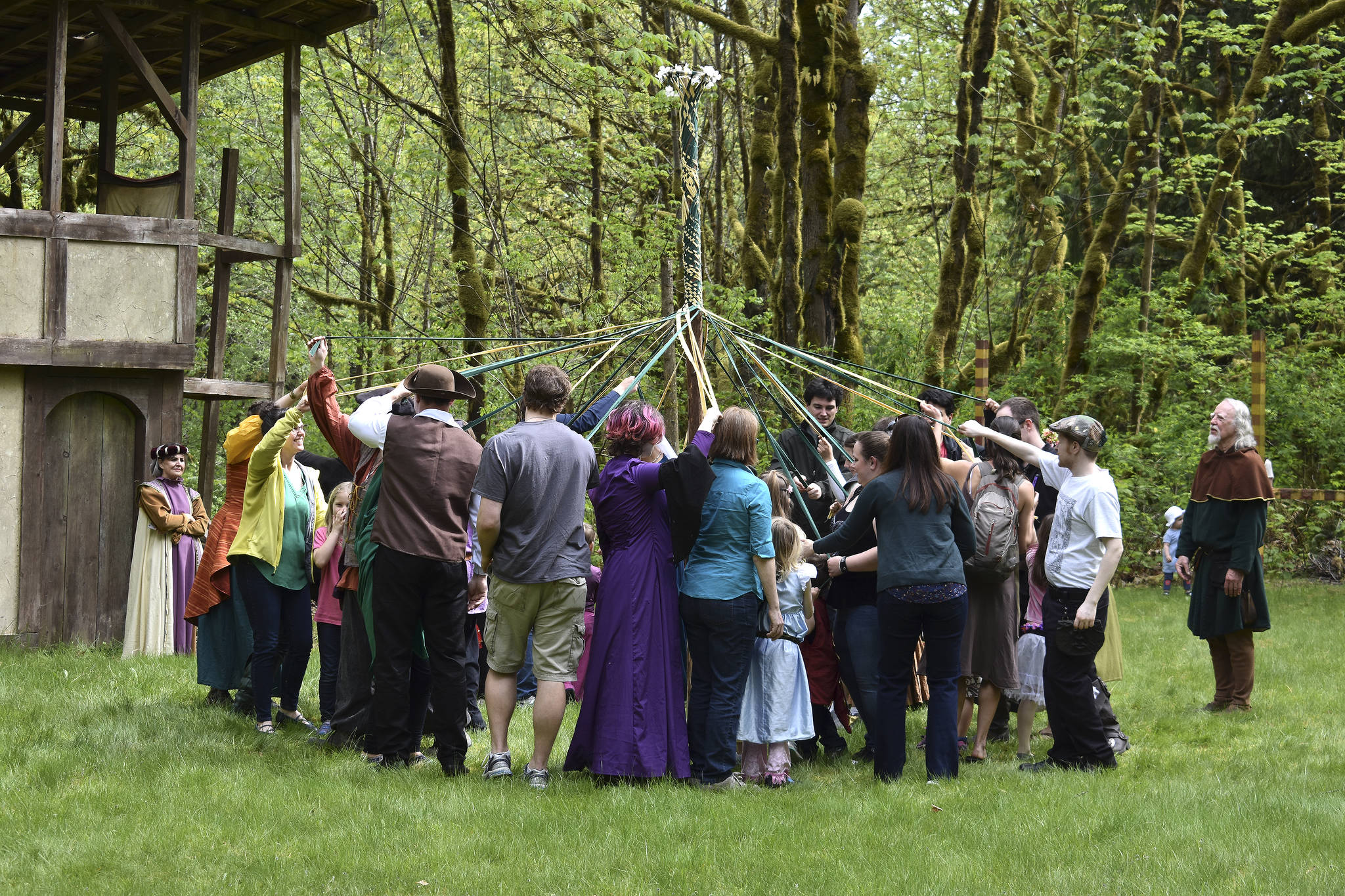 Volunteers and patrons work together to weave in and out to make a May pole. Raechel Dawson/staff photo