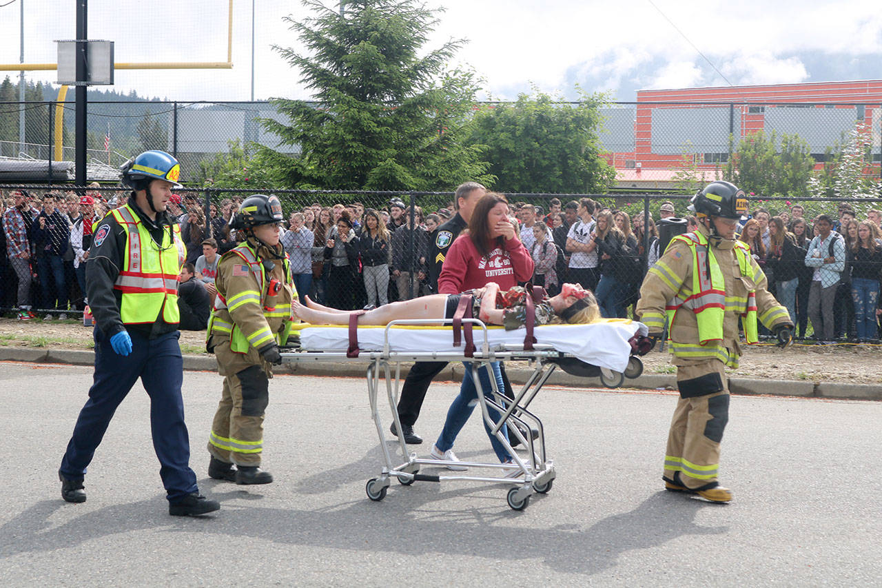A student covered in makeup and fake blood is pulled away on a stretcher and loaded into an ambulance as part of the mock crash. Evan Pappas/Staff Photo