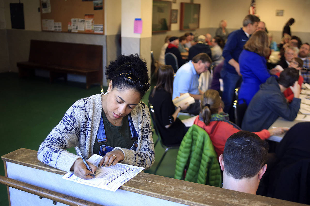 Nashika Hadley fills out a registration form during the 2016 Democratic caucus at the Everett Labor Temple in Everett. (Kevin Clark / Herald file)