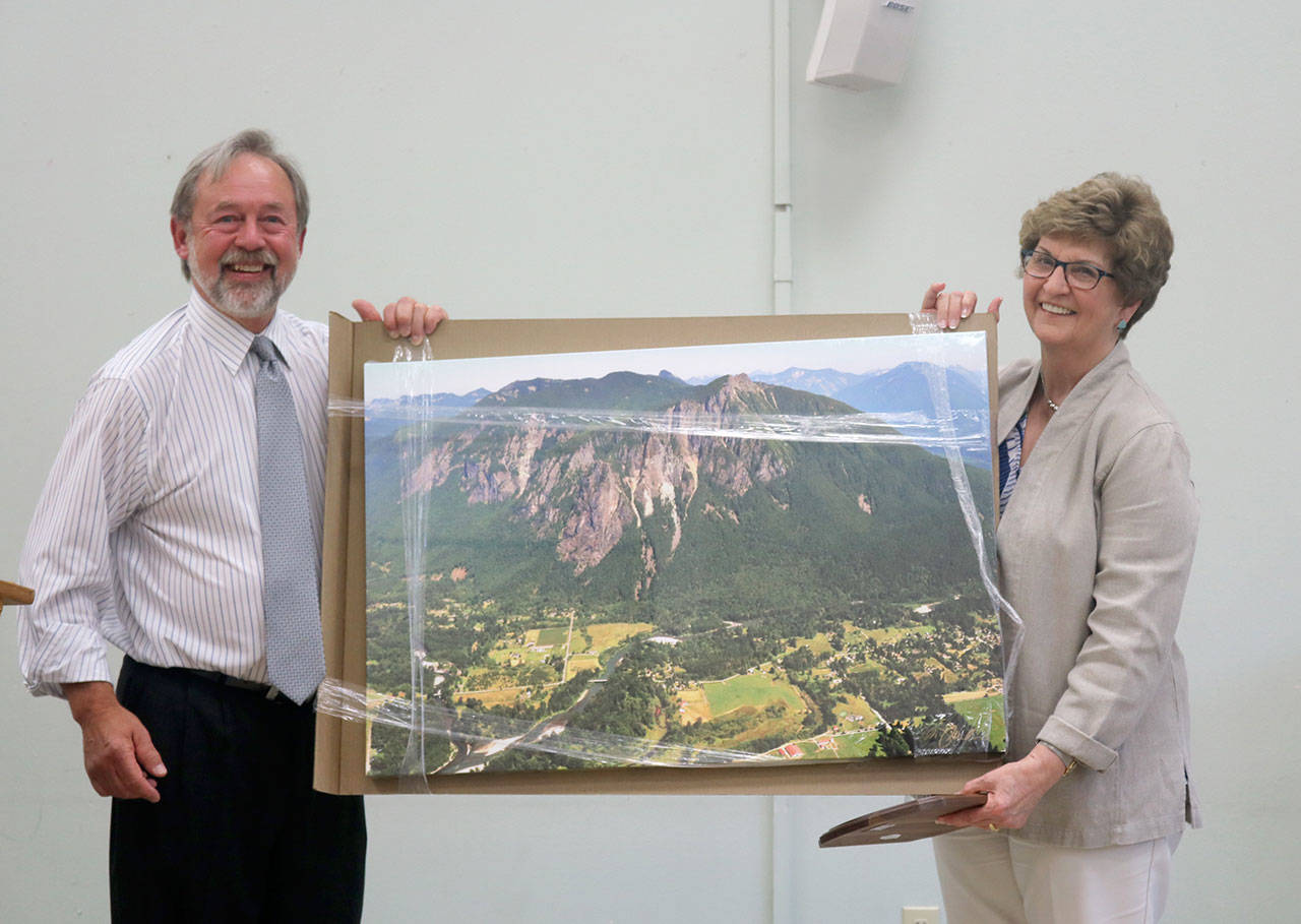 North Bend Mayor Ken Hearing presents gave outgoing council member Jeanne Petterson a large photo of Mount Si as a going away present on behalf of the city. Evan Pappas/Staff Photo