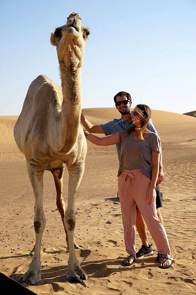 Jake and Madison Leland pet a camel in a desert near Dubai. Photo courtesy of Jake and Madison Leland
