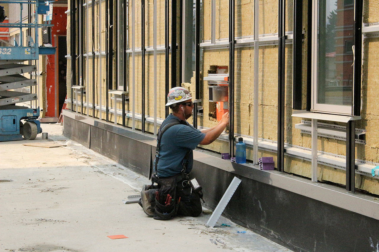 Construction worker installing siding to building. Madison Miller/staff photo.