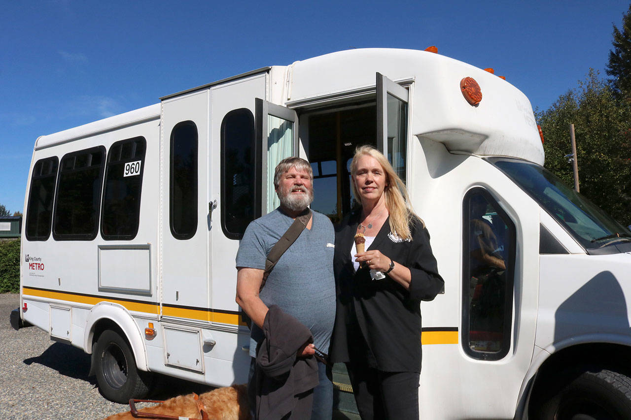Snoqualmie Valley Transportation supporter David Egan and Director Amy Biggs stand together in front of one of the busses. Evan Pappas/Staff Photo