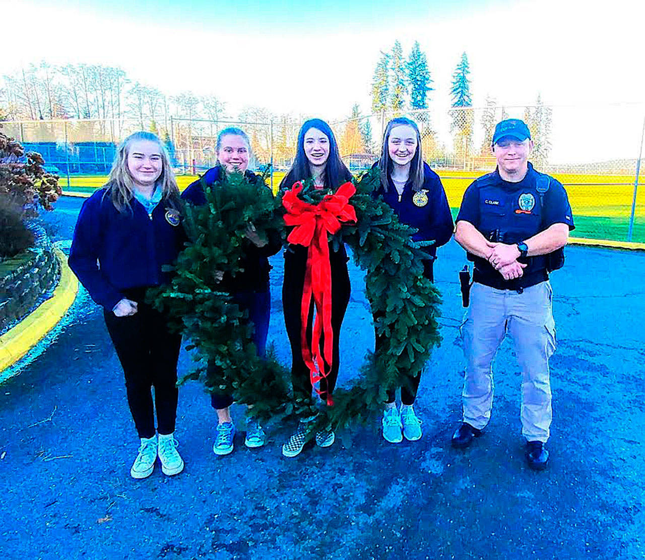 The 40-inch wreath was given to the Duvall Police Department for the third year in a row. From left: Elisabeth Anderson, Bethany Smith, Madison Rose, Emma Chaffin, Officer Cory Clark. Photo by Sarah Thomas