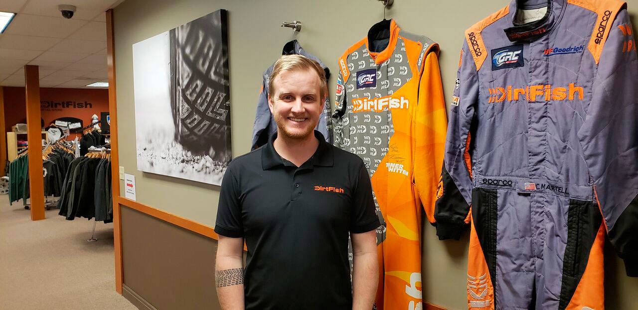 Dirtfish’s media manager Trevor Wert stands against a wall of suits worn by professional Dirtfish racers. Drew Stuart/ Staff Photo