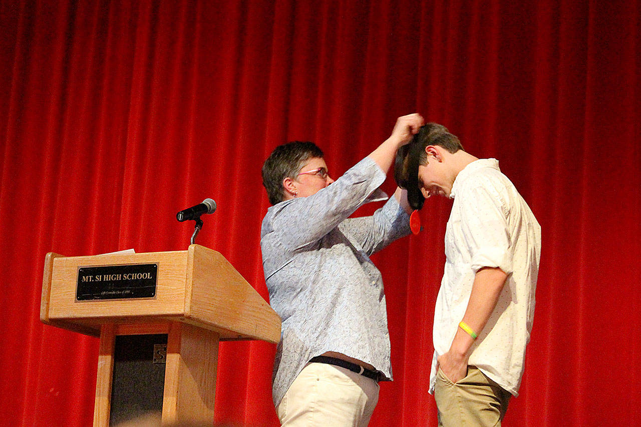 Marcella Murphy gives senior Joe Harris the first AVID medallion that all the AVID seniors will wear at graduation from this year forward. Madison Miller / staff photo