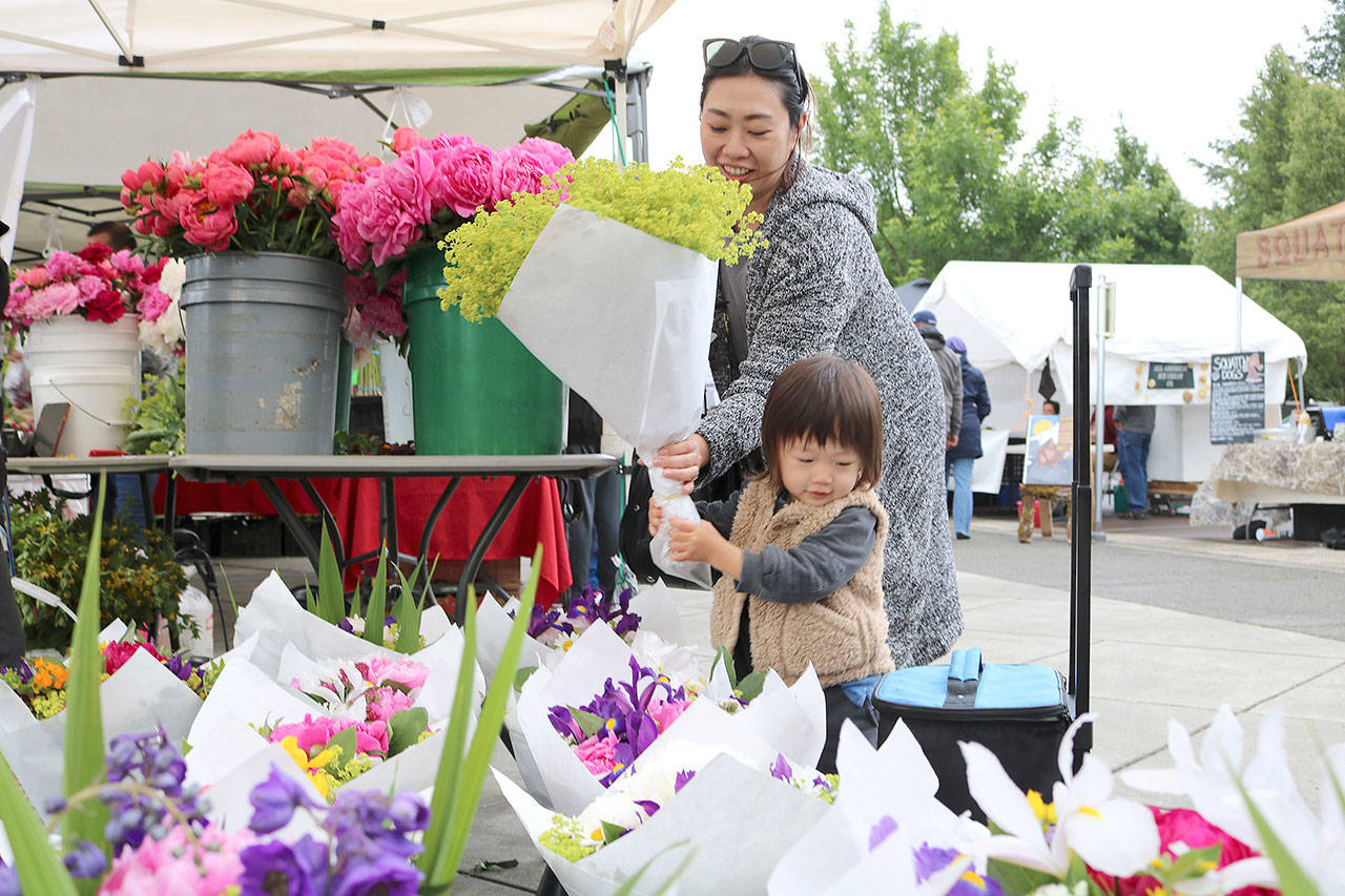 Emi Baba and Aj Baba, 2 of North Bend choose some fresh flowers at the farmers market’s opening day.
