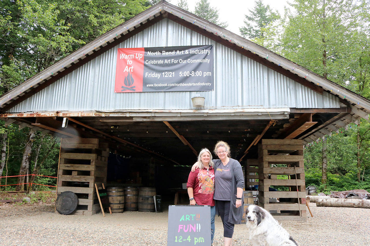 The 1924 train shed roof sits on the property as North Bend Art and Industry raises the money to rebuild the careful deconstructed and catalogued building. Debra Landers, left, and Beth Burrows prepared for the Summer kick off event with Lander’s dog Freyja on Saturday. Evan Pappas/Staff Photo