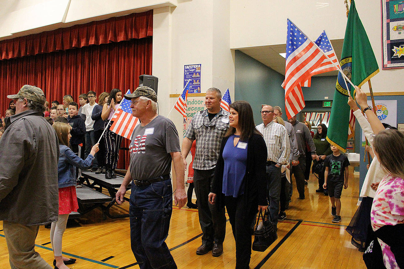 Desi Cuddihy’s fourth-grade students welcome veterans, including Navy veterans Mark and Angie Kennedy (center) as they enter the Snoqualmie Elementary Veterans Day assembly on Nov. 8. Madison Miller / staff photo