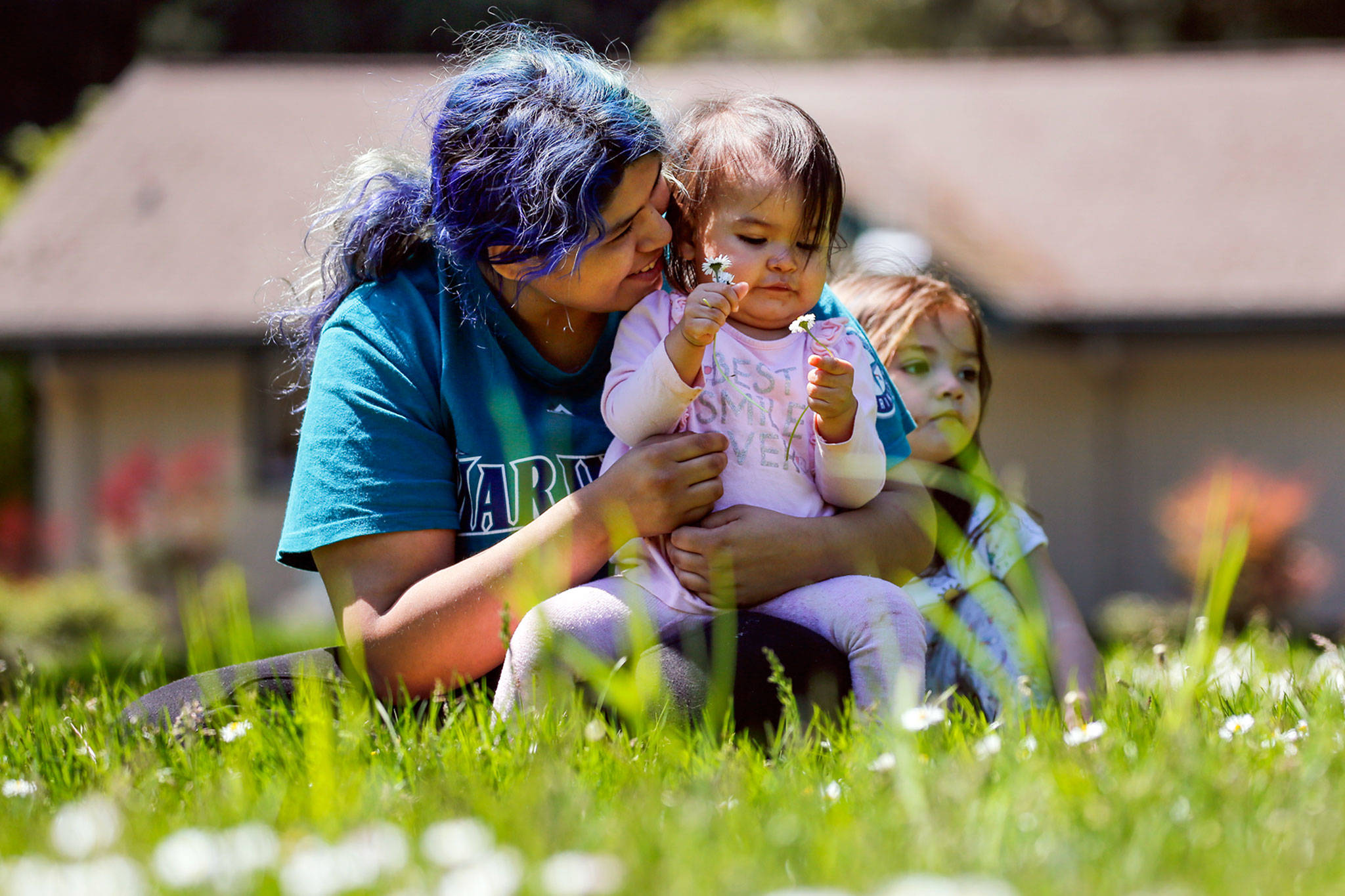 Lavennah Shongutsie hugs daughter Moniqueah Shongutsie-Wesley in the afternoon sun at Forest Park in Everett on Thursday. Temperatures are expected to reach 80 degrees this weekend. (Kevin Clark / The Herald)