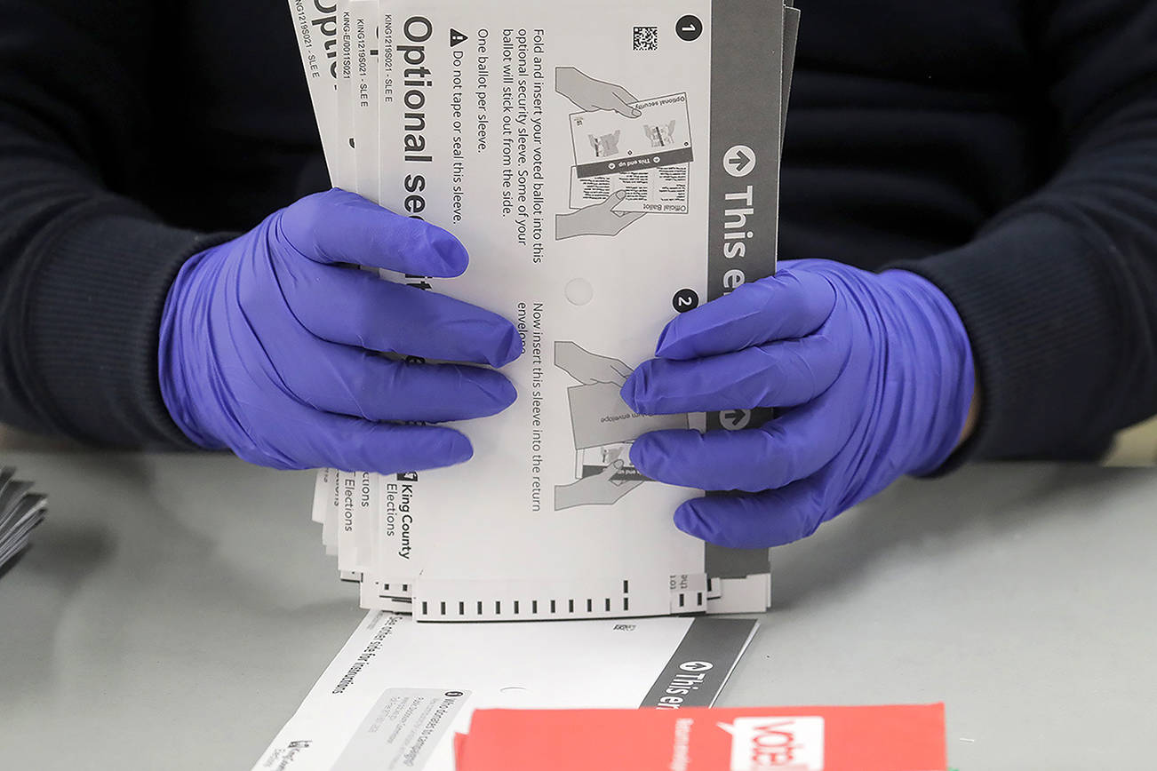 A worker wears gloves while handling ballots from the Washington state primary election, Tuesday, March 10, 2020, at the King County Elections headquarters in Renton, Wash. File photo/The Herald