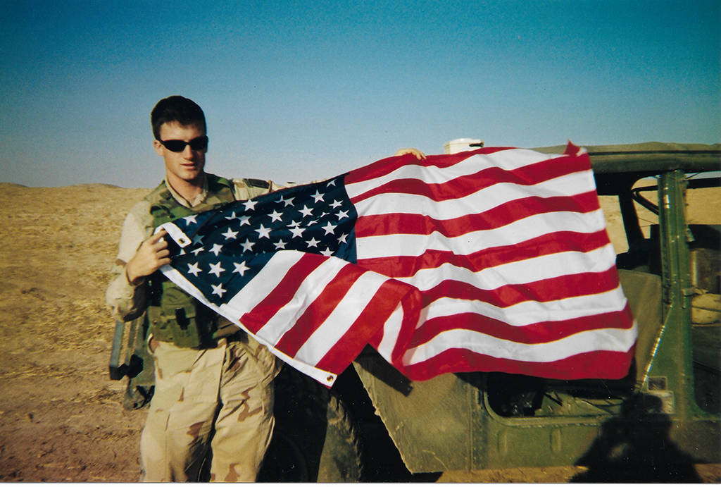 Luke Vilsmeyer poses with the flag he brought back from his first foreign war in Iraq. 	Photo provided by Marc Vilsmeyer