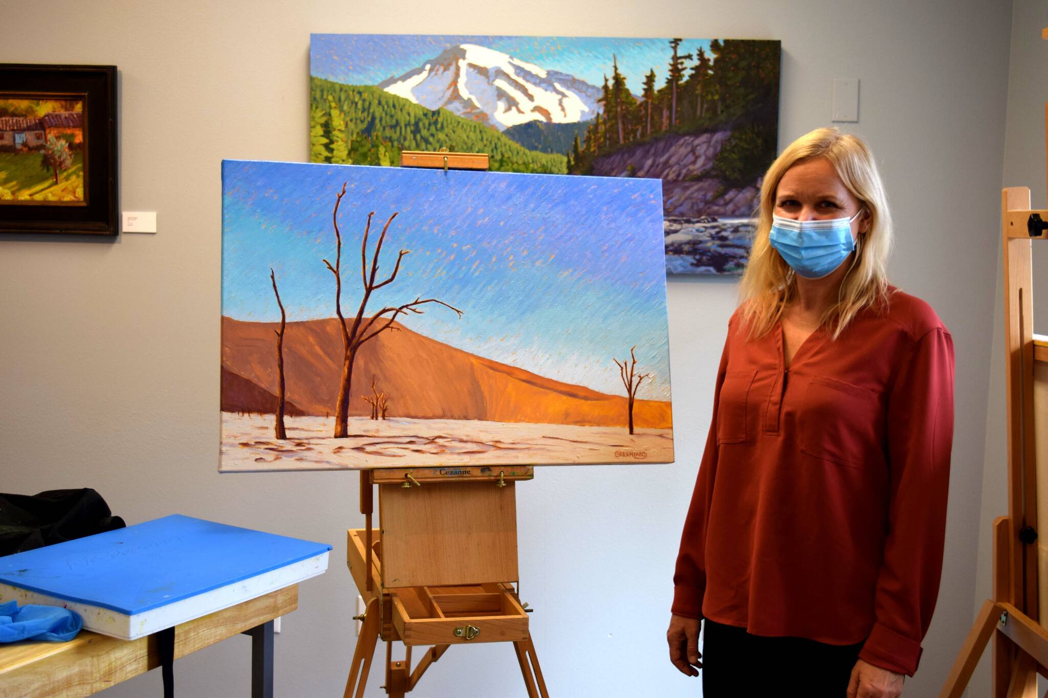 Photo by Conor Wilson/Valley Record
Local artist Britt Greenland poses with a custom painting of a customers trip to Namibia at her gallery in North Bend.