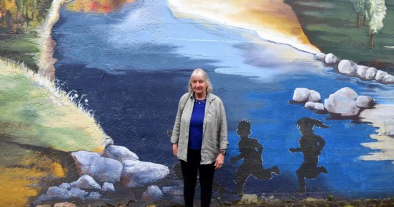 Barbara Center poses in front of a mural at Fall City Art Park. Photo by Conor Wilson/Valley Record