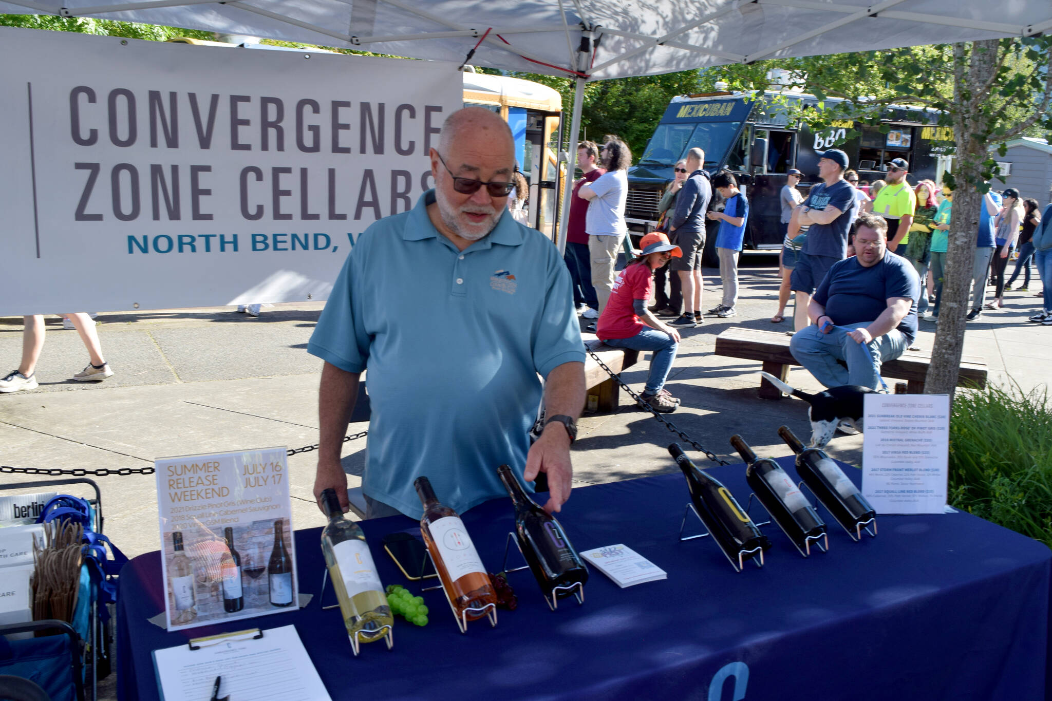 Scott Greenberg, owner of Convergence Zone Cellars winery, points at one of his wines during the North Bend Farmers Market on June 23.