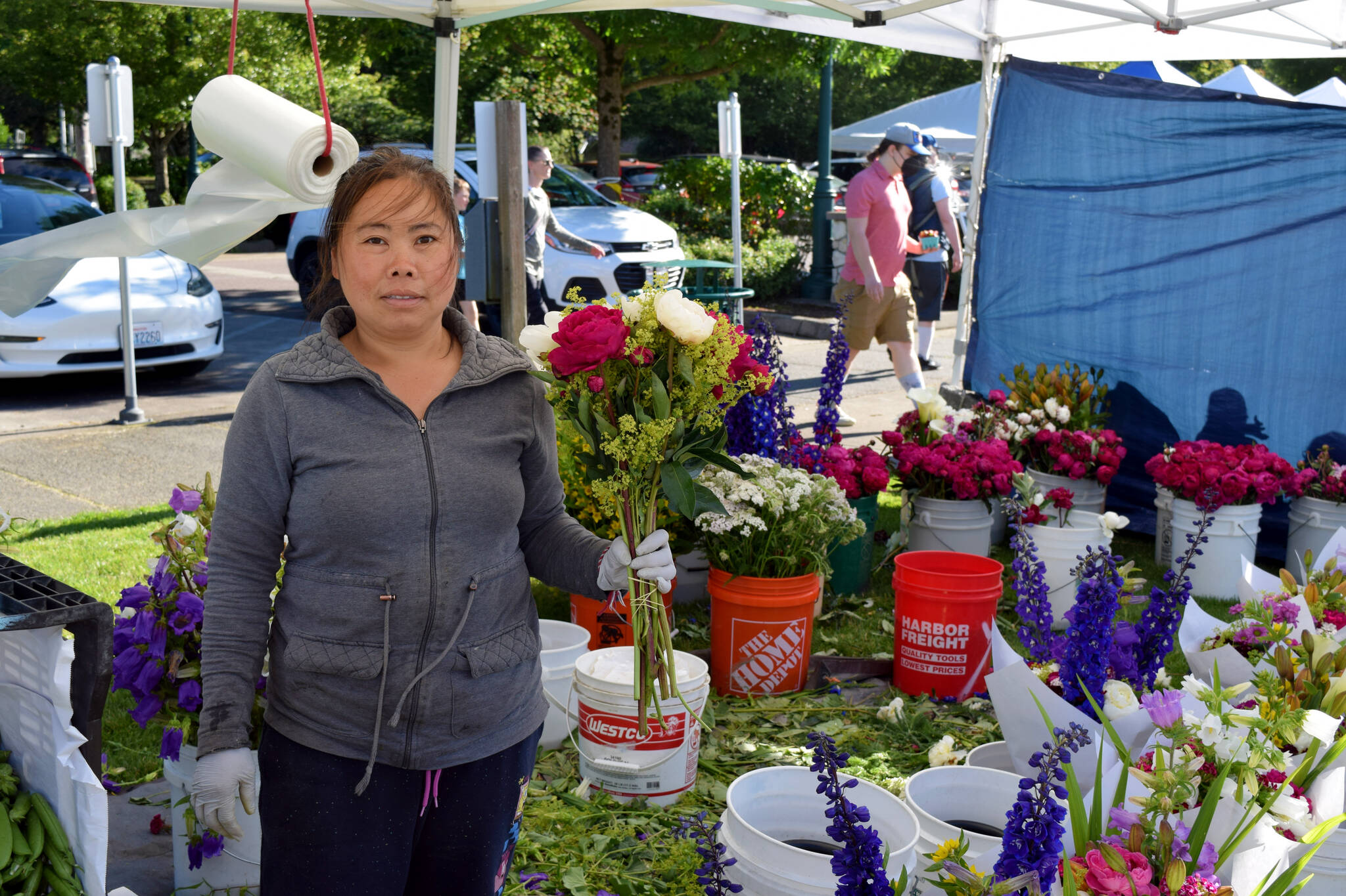 A vendor at The North Bends Farmers market poses with their flowers on June 23.