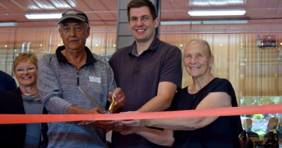 Gary Remlinger (left) and his wife Bonnie (right) join grandson Nathan Sherfey for a ribbon cutting ceremony on Sept. 8. Photo Conor Wilson/Valley Record.