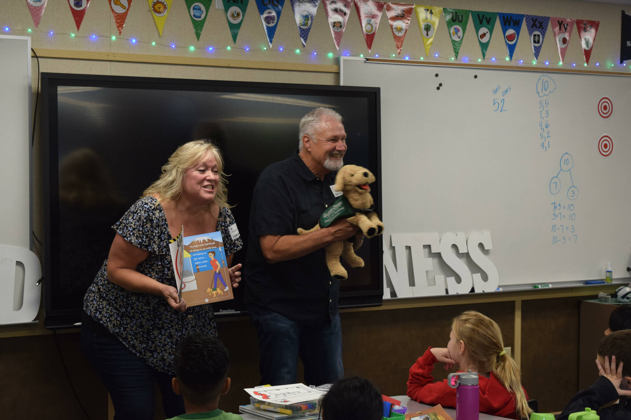 Clark (right) and Karrie Roberts read their book “A Guide Dog named Arby” to students at North Bend Elementary. Photo by Conor Wilson/Valley Record