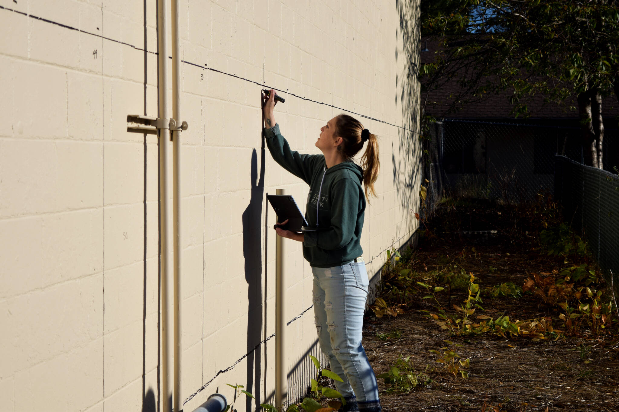 Sarah Hughes marks out squares for a new mural in North Bend on Nov. 9. Photos Conor Wilson/Valley Record.