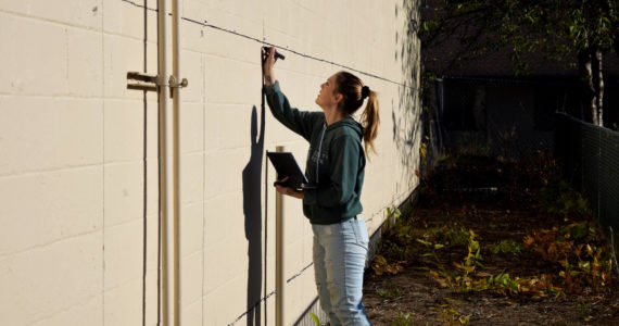 Sarah Hughes marks out squares for a new mural in downtown North Bend on Nov. 9. Photos Conor Wilson/Valley Record.
