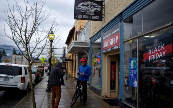 Brian Davis films outside of Singletrack Cycles in downtown North Bend on Nov. 22. Photo by Conor Wilson/Valley Record