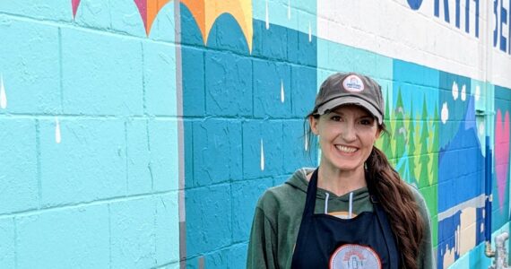 Hayley Raff, owner of Pressed on Main, poses in front of a mural on the side of her business at 208 Main Ave. S., North Bend. Photo by Conor Wilson/Valley Record