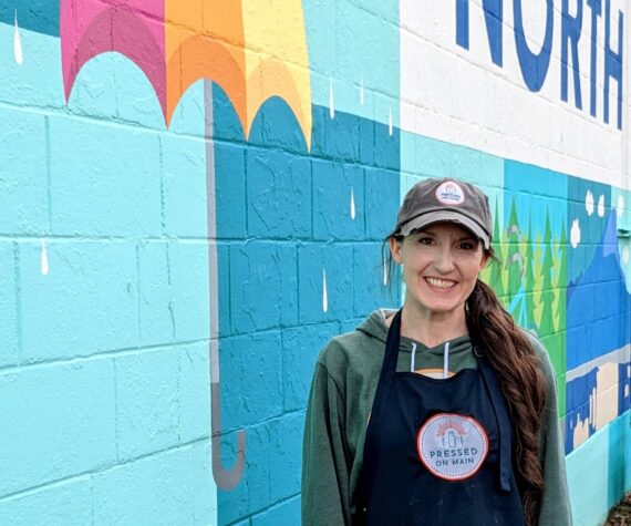 Hayley Raff, owner of Pressed on Main, poses in front of a mural on the side of her business at 208 Main Ave. S., North Bend. Photo by Conor Wilson/Valley Record