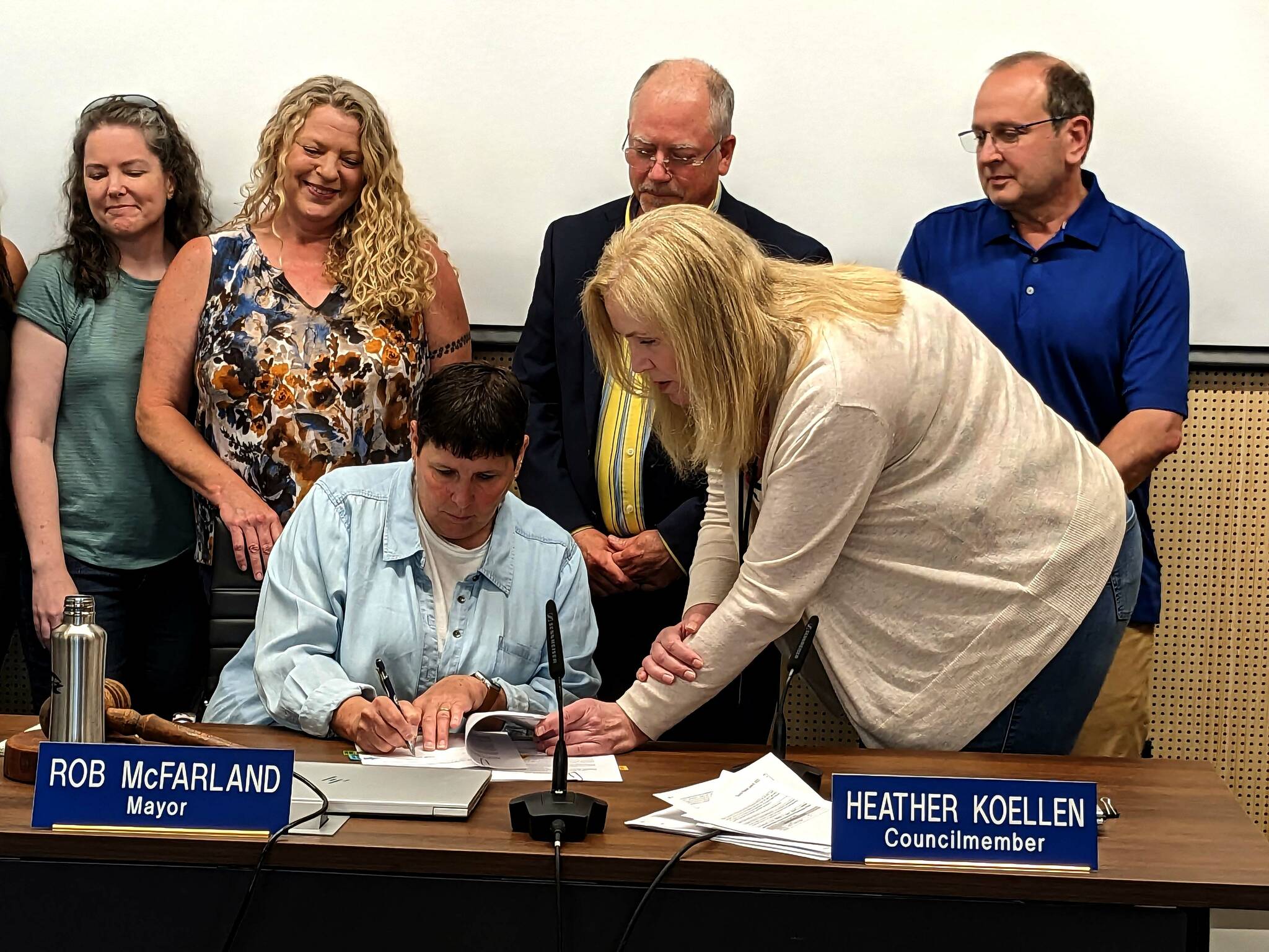 Sallal Board President Denise Smutny signs the water supply agreement at the North Bend City Council meeting on June 6 beside North Bend Mayor Rob McFarland, back center. (Photo by Conor Wilson/Valley Record)