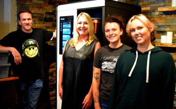 Tanya Guinn, middle left, poses with staff members in front of Trail Youth’s new coffee roaster. Photo by Conor Wilson/Valley Record.