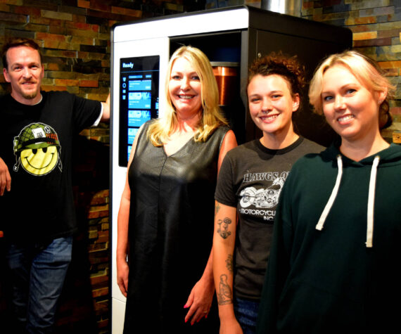 Tanya Guinn, middle left, poses with staff members in front of Trail Youth’s new coffee roaster. Photo by Conor Wilson/Valley Record.