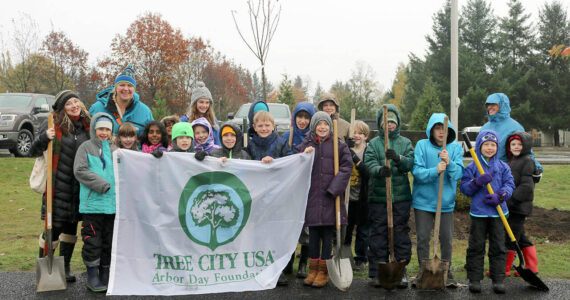 File Photo
Volunteers pose with the Tree City USA banner before getting to work on planting trees in North Bend.