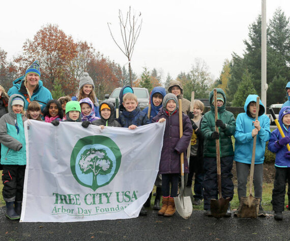 File Photo
Volunteers pose with the Tree City USA banner before getting to work on planting trees in North Bend.