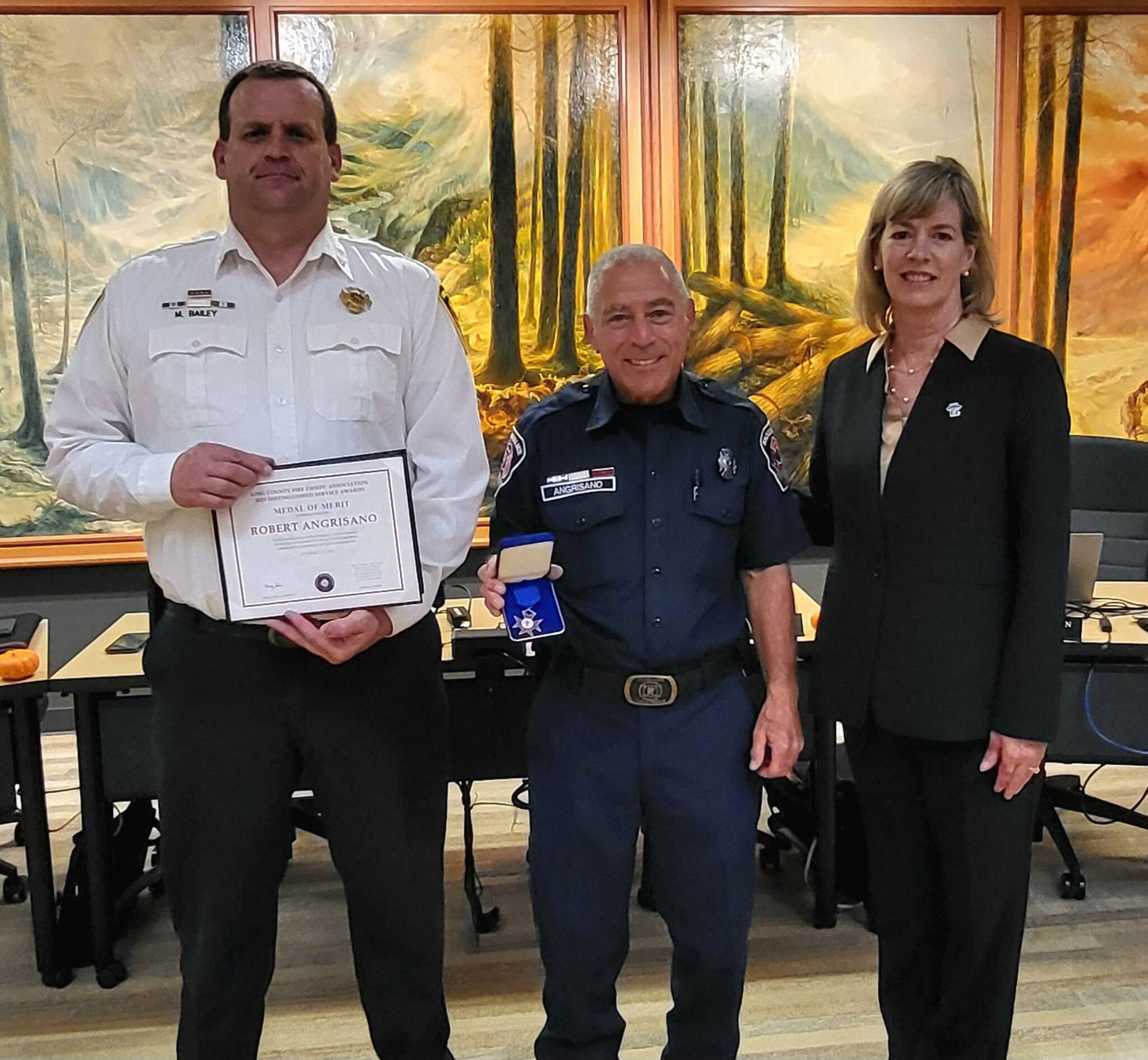 Courtesy Photo. Volunteer Firefighter Robert Angrisano, center, is honored at a city council meeting alongside Mayor Katherine Ross and Interim Fire Chief Mike Bailey.