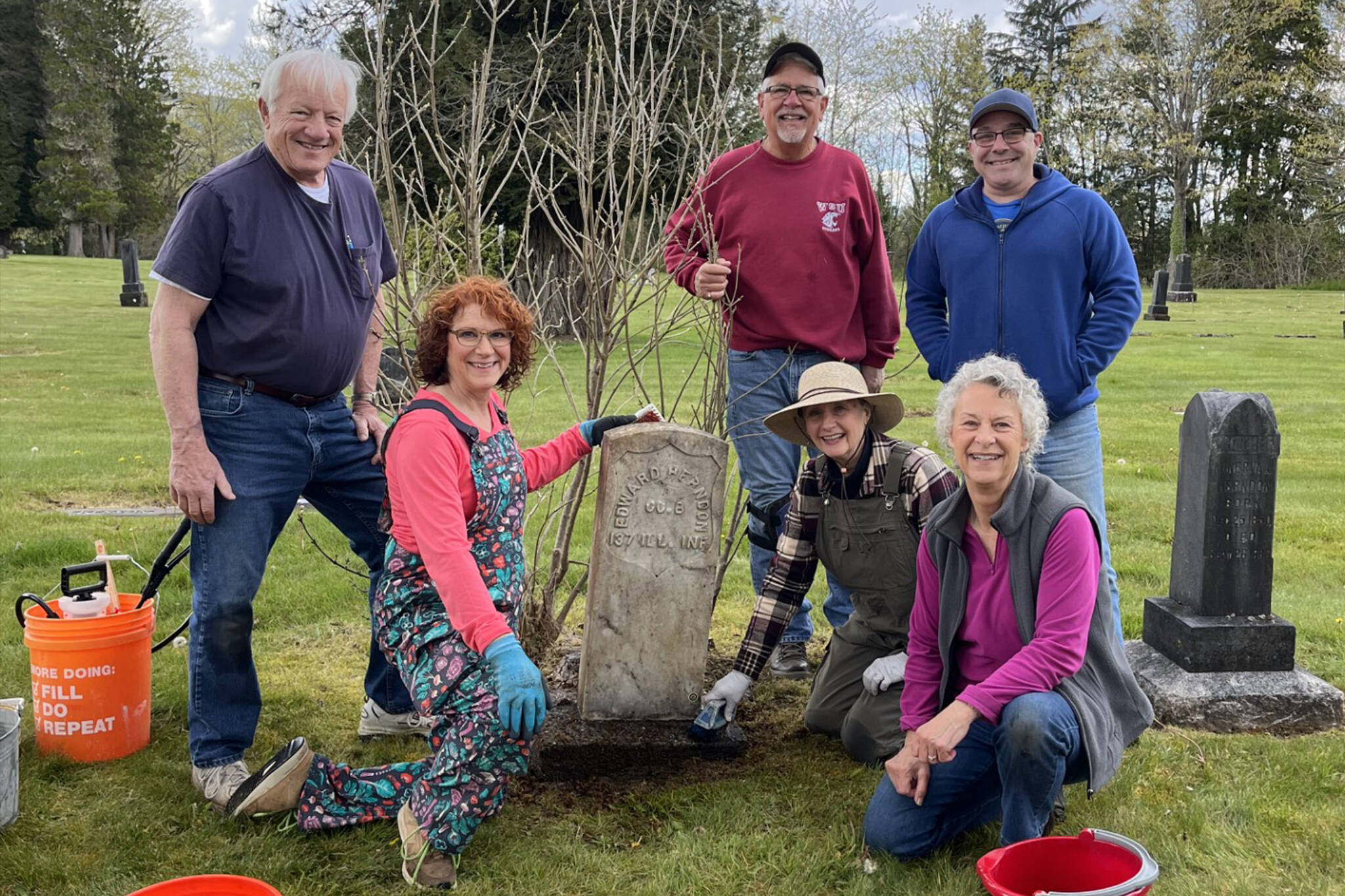 Volunteers clean a headstone at the Fall City Cemetery. From left: (standing) Gene Stevens, Rick Divers, Richard Heilser; (kneeling) Anne Neilson, Donna Driver-Kummen, Cindy Parks. (Photo courtesy of Cindy Parks.)